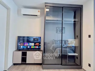 Modern bedroom with sleek glass wardrobe and wall-mounted TV, perfect for contemporary living.