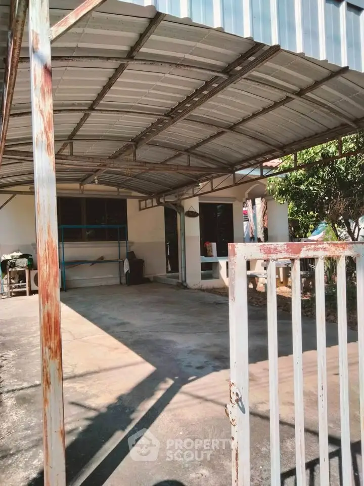 Spacious covered parking area with metal roof and gated entrance in a residential property.