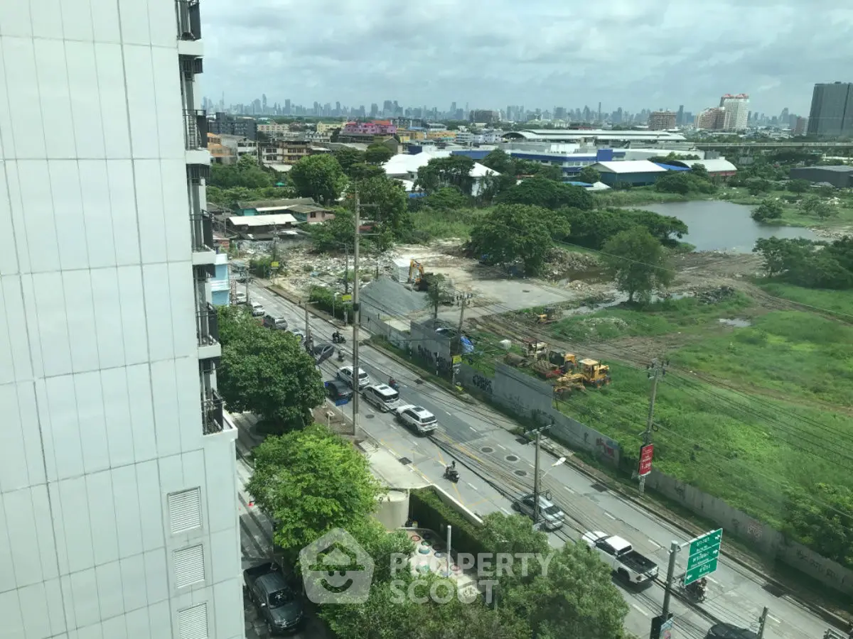 Cityscape view from high-rise building overlooking urban development and greenery.