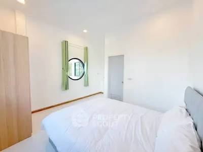 Bright and airy bedroom with modern decor and unique circular window.