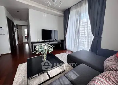 Modern living room with sleek furniture and large window offering natural light.