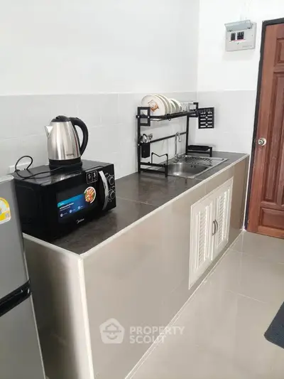 Modern kitchen with sleek countertop, microwave, and dish rack in a compact layout.