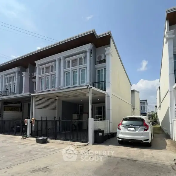 Modern townhouse with car parked in driveway, featuring contemporary architecture and spacious layout.