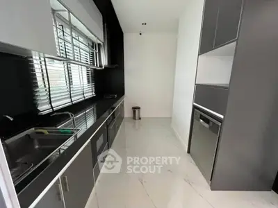 Sleek modern kitchen with black and white design, featuring built-in appliances and ample natural light.