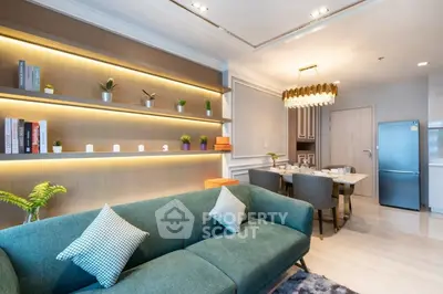 Modern living room with stylish decor and dining area, featuring a green sofa and elegant lighting.