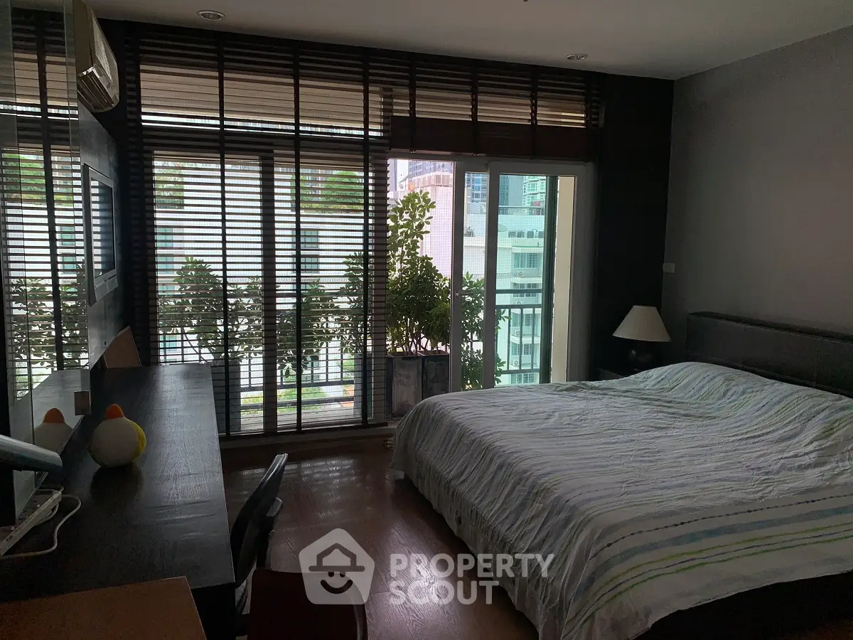 Cozy bedroom with large windows and balcony view, perfect for urban living.