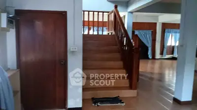 Spacious open-plan living area with wooden staircase and large windows