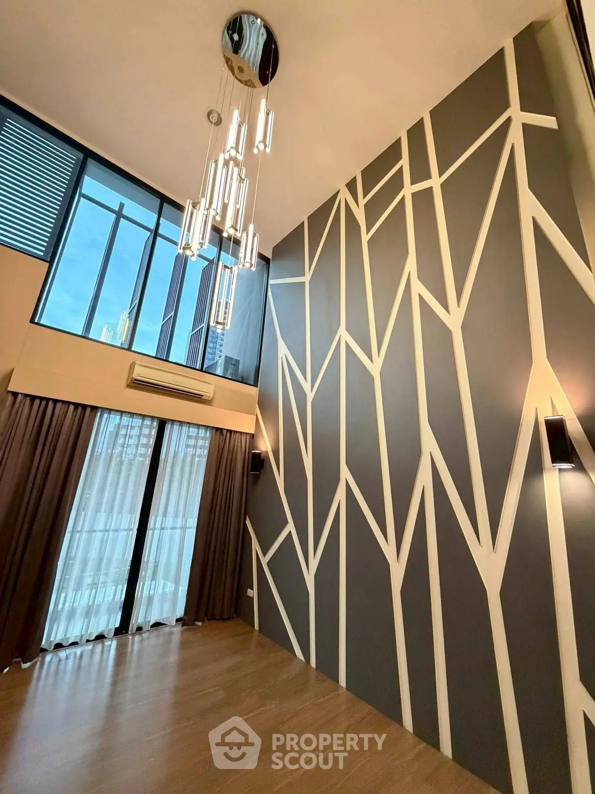 Stunning modern living room with high ceilings and unique geometric wall design.