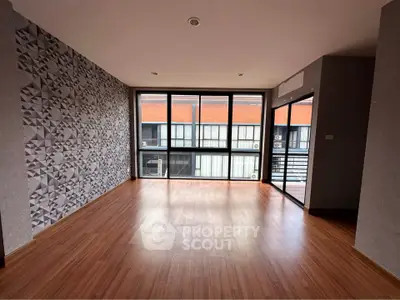 Spacious modern living room with large windows and stylish geometric accent wall.