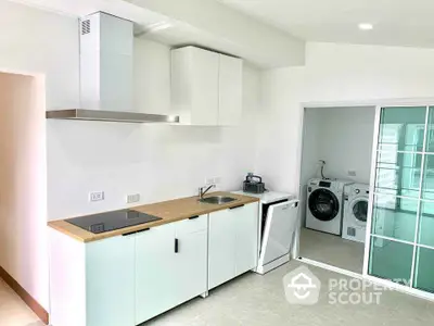 Modern kitchen with sleek appliances and adjacent laundry area in a bright, minimalist design.