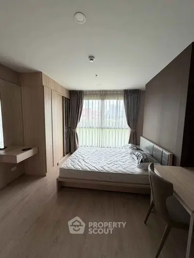 Modern bedroom with large window and stylish furnishings in a contemporary apartment.