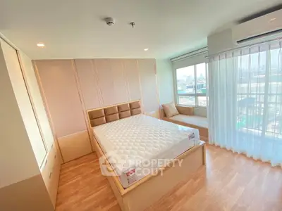 Spacious bedroom with large windows and modern decor in a bright apartment.
