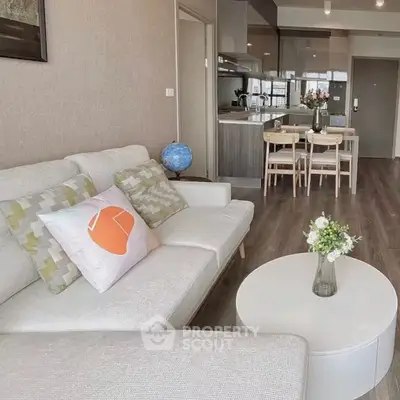 Modern living room with open kitchen, stylish decor, and cozy seating area.
