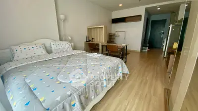 Spacious bedroom with modern decor and study area, featuring wooden flooring and cozy ambiance.