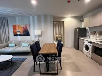 Modern open-plan living room with kitchen, featuring sleek furniture and appliances.