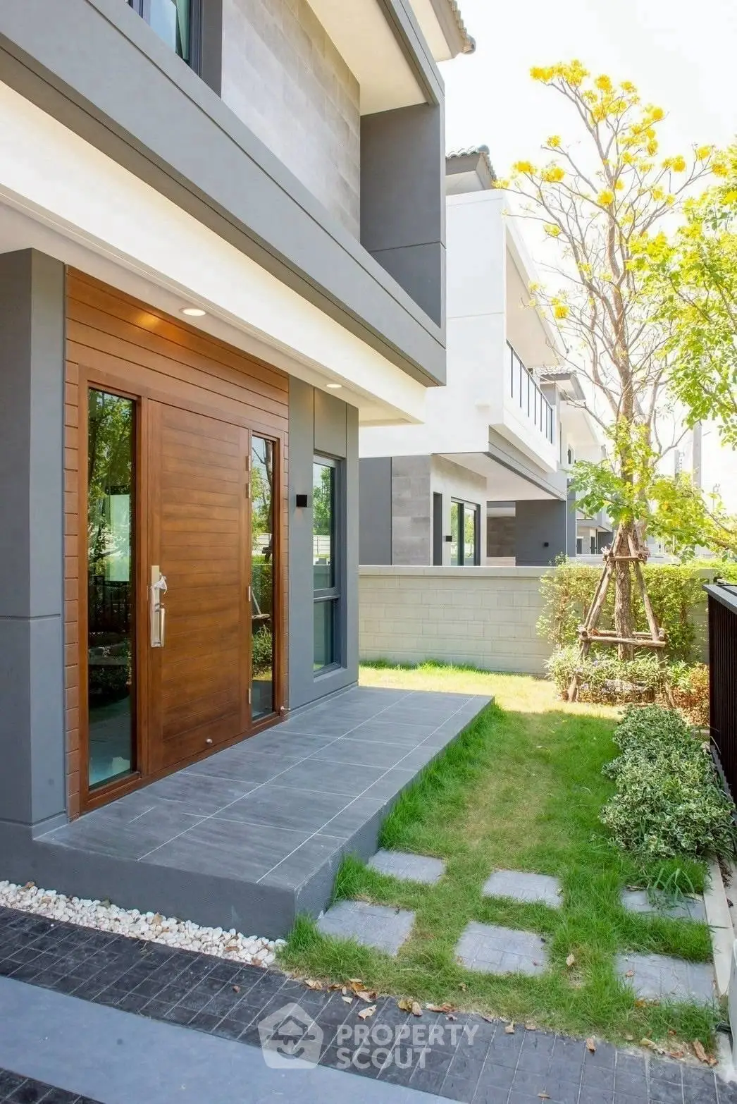 Modern townhouse entrance with sleek wooden door and landscaped garden