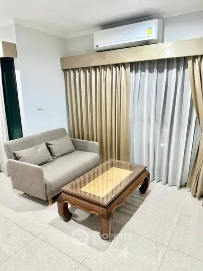 Cozy living room with elegant sofa and wooden coffee table, complemented by floor-to-ceiling curtains and air conditioning.