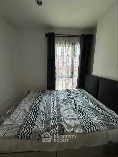 Cozy bedroom with large window and stylish bedding in modern apartment.