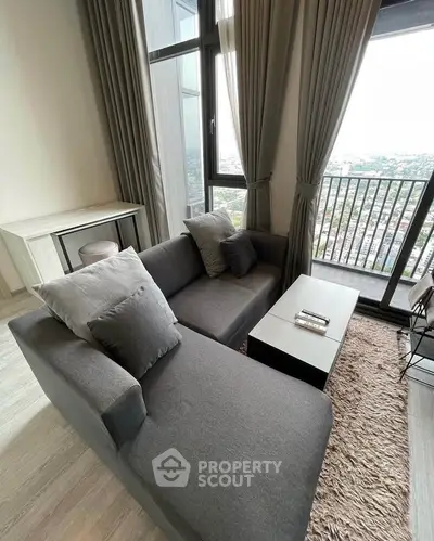 Stylish living room with modern gray sofa and city view balcony, perfect for urban living.