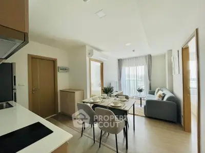 Modern open-plan living room and kitchen with stylish dining area in a bright apartment.