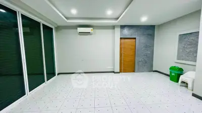 Spacious modern room with tiled flooring and large windows, perfect for versatile living space.