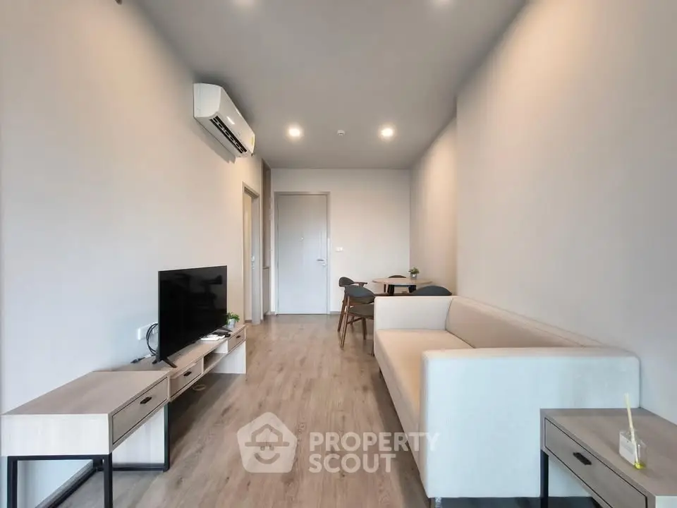 Modern living room with sleek furniture and minimalist design, featuring a cozy sofa and flat-screen TV.
