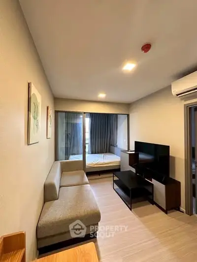 Modern living room with sleek furniture and a view into the bedroom, showcasing open layout design.