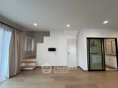 Spacious modern living room with wooden flooring and glass partition kitchen