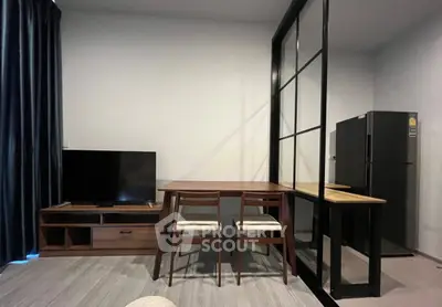 Modern living room with sleek furniture and glass partition, featuring a TV and dining area.