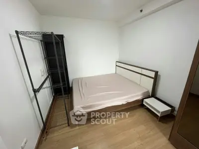 Cozy bedroom with minimalist design featuring a bed, nightstand, and open shelving unit.