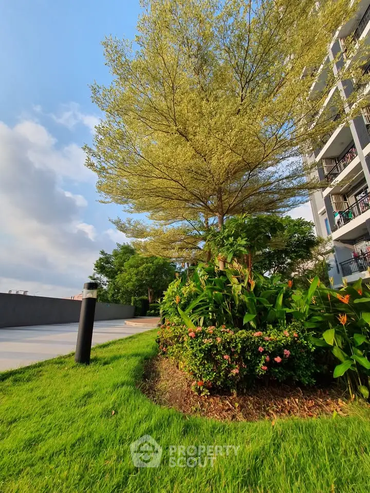 Lush garden area in modern residential complex with vibrant greenery and clear blue sky.