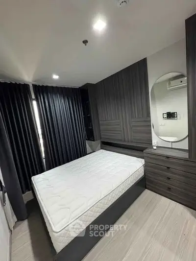 Modern bedroom with sleek dark wood furniture and large window with blackout curtains.