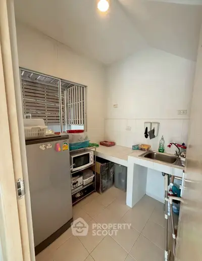 Compact kitchen with modern appliances and open layout, featuring a fridge, microwave, and sink area.