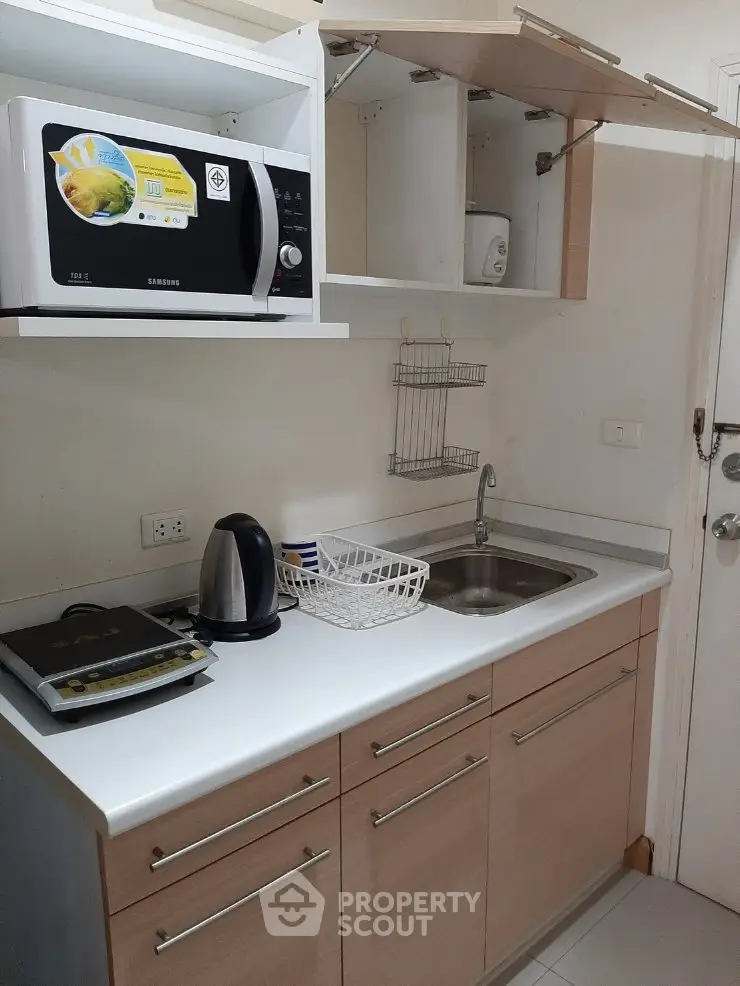 Compact kitchen with modern appliances and sleek cabinetry in a cozy apartment.