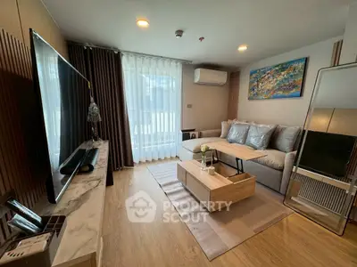 Modern living room with stylish decor, large TV, and natural light from floor-to-ceiling windows.