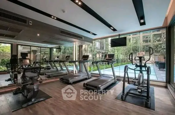Modern gym with state-of-the-art equipment and large windows overlooking lush greenery.