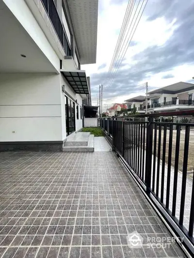 Modern townhouse exterior with spacious tiled patio and sleek black railing