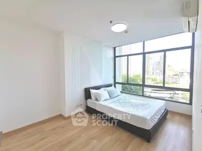 Spacious bedroom with large window offering stunning city views, modern decor, and natural light.