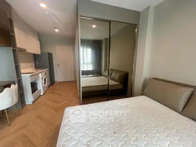 Modern studio apartment with cozy bedroom and compact kitchen featuring washing machine and oven.