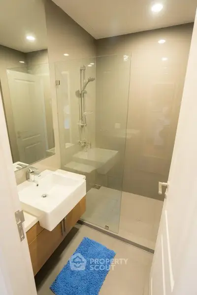 Modern bathroom with glass shower and sleek vanity in contemporary home.