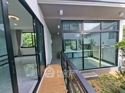 Modern home with large windows and balcony overlooking lush greenery, perfect for serene living.