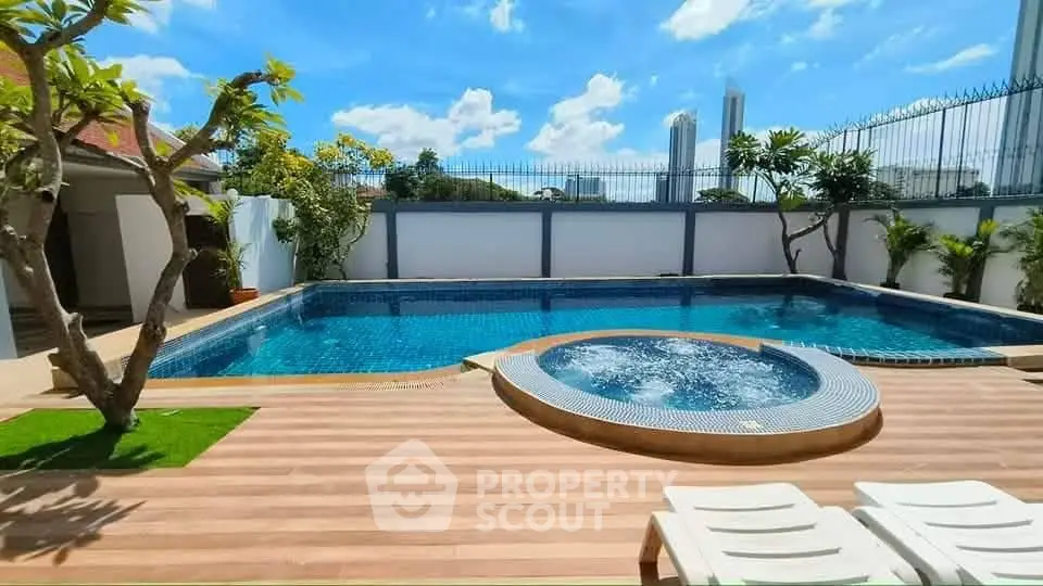 Luxurious outdoor pool area with jacuzzi and sun loungers, perfect for relaxation and leisure.