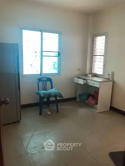 Minimalist room with natural light, featuring a window, chair, and small desk, ideal for creative use.