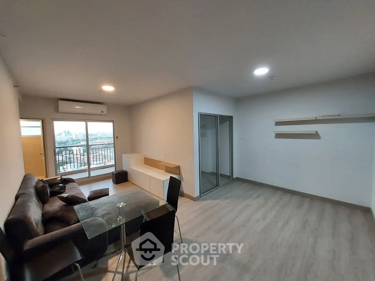 Modern living room with balcony and city view, featuring sleek furniture and open layout.