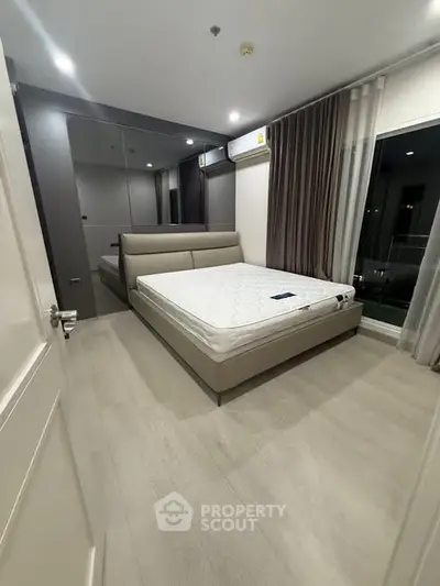Modern bedroom with sleek design, featuring a comfortable bed and large windows for natural light.