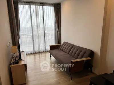 Modern living room with stylish sofa and floor-to-ceiling windows offering a panoramic city view.