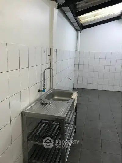 Spacious tiled kitchen with stainless steel sink and open shelving, ideal for modern renovations.