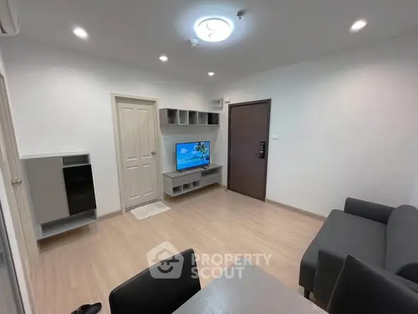 Modern living room with sleek furniture and wall-mounted TV in a cozy apartment.