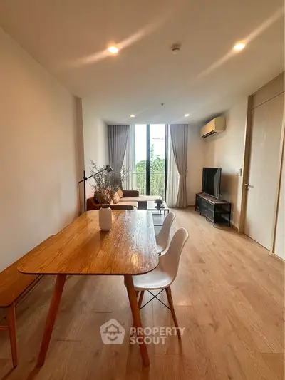 Spacious modern living room with wooden flooring and large window view.