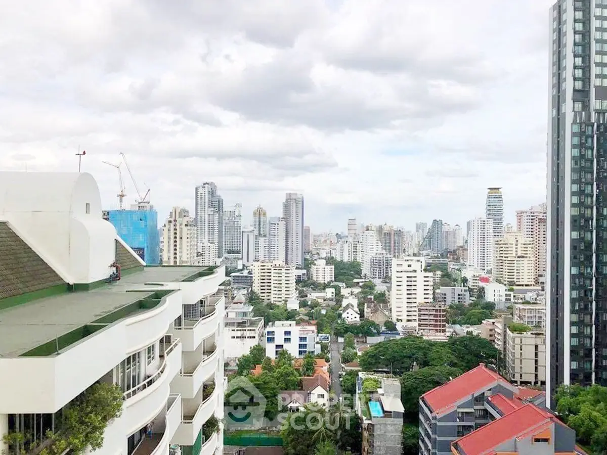 Stunning cityscape view from a high-rise building showcasing urban skyline and lush greenery.